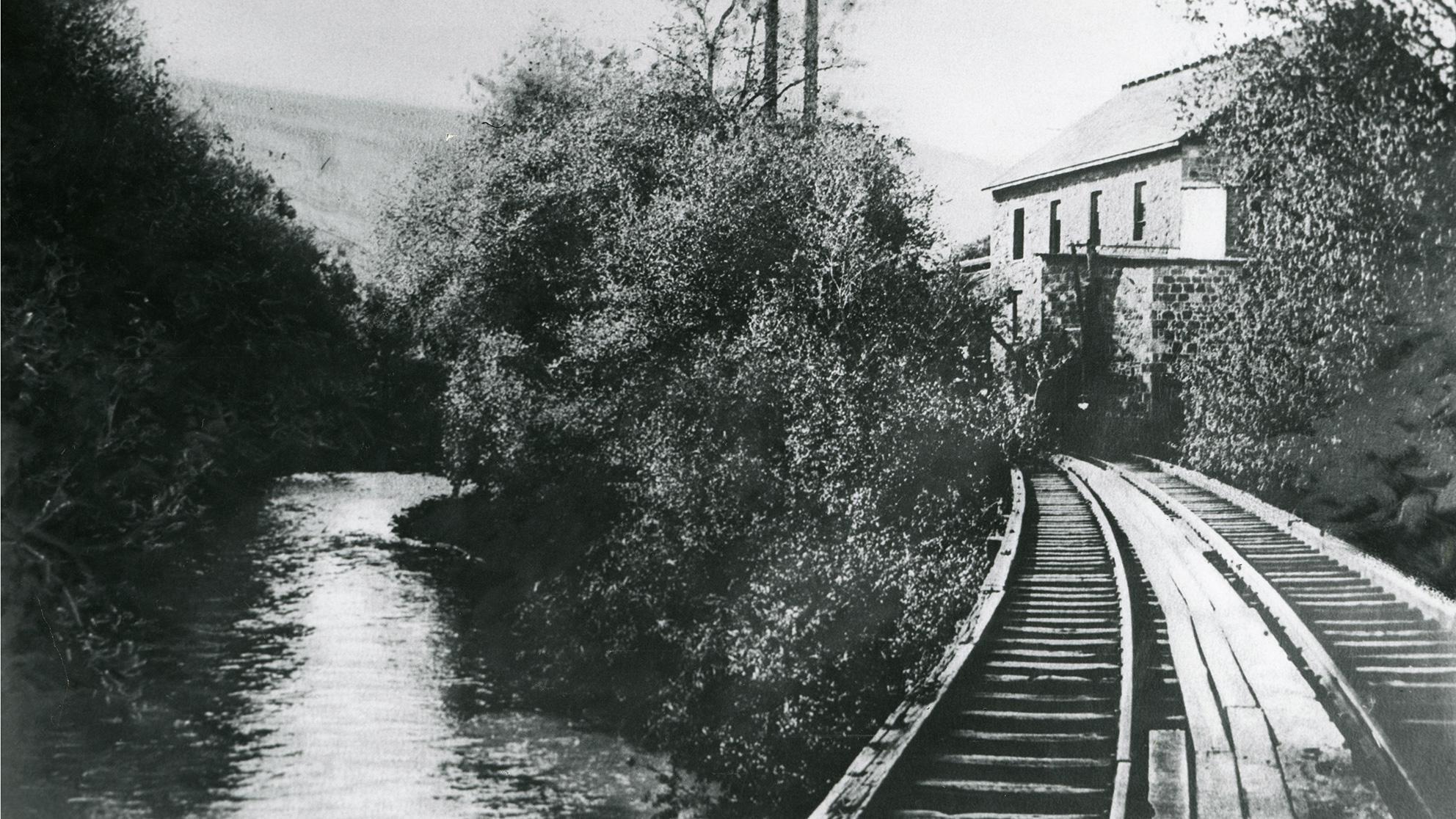 Archival black and white photo of train tracks along a river